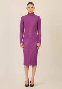 Vestido de punto acanalado púrpura con cuello alto, mangas largas y un cinturón plateado en la cintura. Ajustado al cuerpo y de longitud midi.