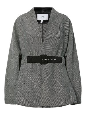 Svart-hvitt mønstret jakke med et geometrisk design, med høy krage, lange ermer og et svart belte rundt midjen.
