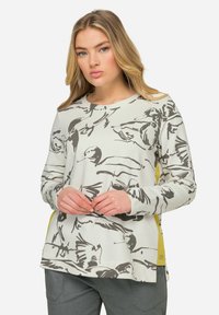 Sweatshirt gris clair avec un imprimé d'oiseau noir, col rond, manches longues et accents jaunes sur les côtés, fabriqué en tissu doux.
