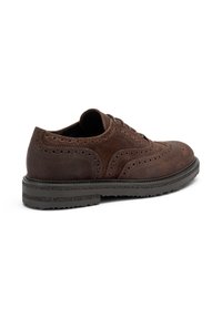 Scarpa in suede marrone caratterizzata da dettagli brogue, design con lacci e suola in gomma a contrasto con battistrada testurizzato per una maggiore aderenza.