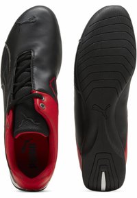 Černé kožené boty s červenými detaily, vybavené síťovaným jazykem, texturovanou podrážkou a význačným logem na boku a stélce.