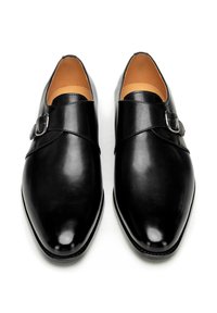 Paar polierter schwarzer Ledermönch-Riemen-Herrenschuhe mit silbernen Schnallen, von oben auf weißem Hintergrund gezeigt.