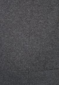 Texture de tissu tricoté gris foncé avec des mailles visibles et un ourlet côtelé en bas.