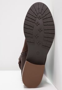 Hnědá sukně kotníková obuv s gumovou podrážkou a texturovaným vzorkem na profilu, se zipem na boku pro snadný přístup.