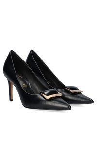 Zapatos de tacón altos de cuero negro con punta afilada, detalle de hebilla con acentos dorados en el empeine y un tacón de aguja delgado.