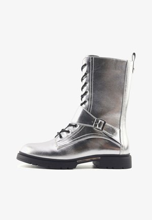 Srebrne metaliczne buty wojskowe z przodem na sznurówki, bocznym paskiem na klamrę i teksturowaną cholewką. Posiadają wytrzymałą czarną gumową podeszwę.