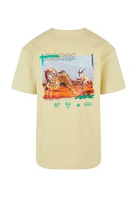 Light yellow t-shirt featuring a graphic print of a cheetah and antelope, with green and blue accents and abstract patterns.