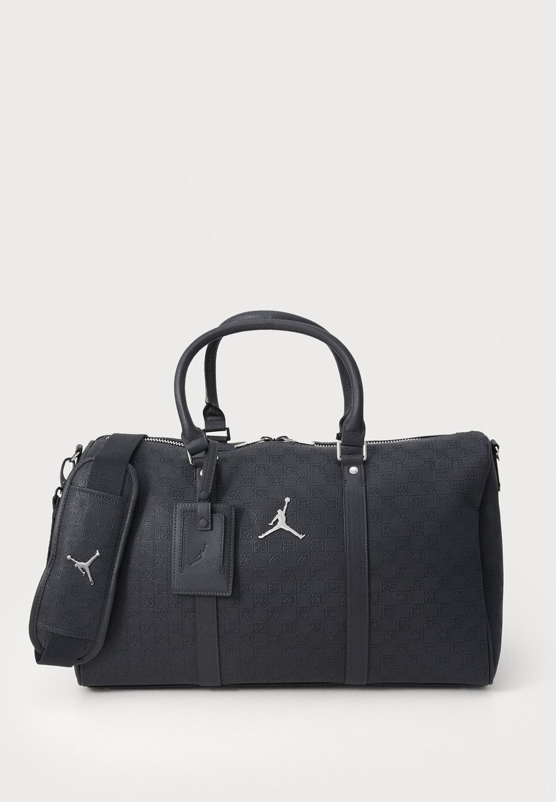 Schwarze Duffle-Tasche aus strukturiertem Material, mit doppelten Griffen, verstellbarem Riemen, silbernen Beschlägen und eingeprägtem Logomuster. Reißverschlussverschluss oben.