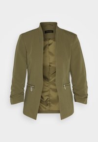 Blazer femme vert olive avec manches froncées, devant ouvert et poches zippées, montrant une doublure intérieure lisse.
