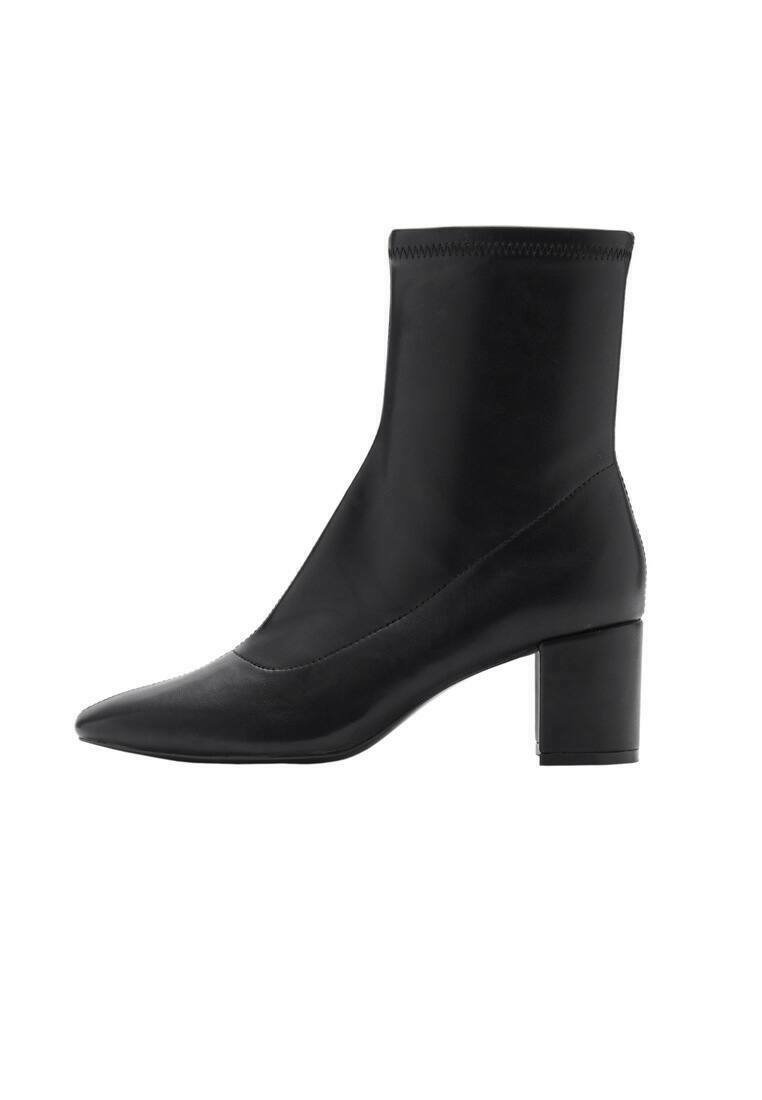 Botte noire à la cheville en cuir lisse, avec un bout pointu et un talon carré. Le design est épuré avec une tige ajustée à la cheville.