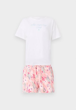 Λευκό κοντομάνικο μπλουζάκι με μπλε κείμενο «slow morning club» συνδυασμένο με ροζ σορτς με λουλουδάτο σχέδιο.