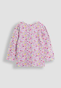 Camiseta de manga larga para niños con estampado colorido de flores y hadas en rosa, amarillo, morado y rojo sobre fondo blanco.