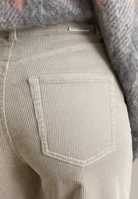 Helle beige Cordhosen mit geripptem Textur. Verfügt über eine Gesäßtasche mit sichtbaren Nähten und einem Etikett mit der Aufschrift "Marc O'Polo Denim".