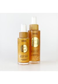 Två gyllene kroppsvårdsprodukter: en mist i en transparent flaska med ett bambulock, och en olja i en hög, liknande flaska. Guldaccenter syns.