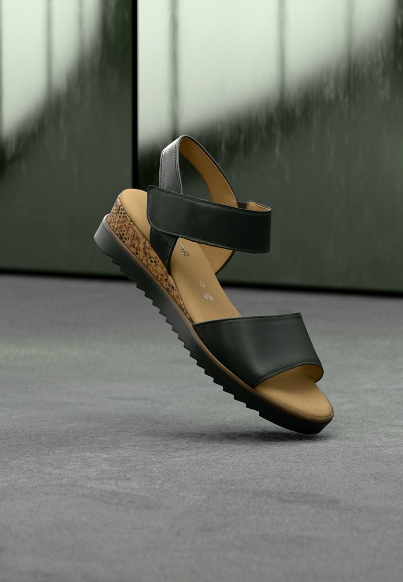 Μαύρο σανδάλι με δύο φαρδιές λουριά και μεσαία σόλα με υφή φελλού. Διαθέτει μαύρη λαστιχένια εξωτερική σόλα με αυλακωτό σχέδιο για πρόσφυση.