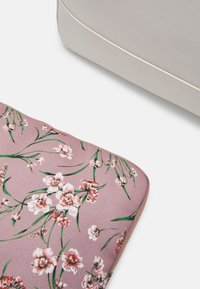 Housse d'ordinateur portable à motif floral sur fond rose avec des fleurs blanches et des tiges vertes, fermeture éclair, tissu texturé et fermeture éclair avec accent doré.