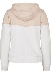 Veste à capuche manches longues, partie supérieure beige et partie inférieure blanche, avec poignets et ceinture élastiques.