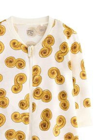 Tutina bianca con zip caratterizzata da motivi a conchiglia di lumaca gialla. Realizzata in tessuto morbido, con maniche lunghe e scollatura rotonda.