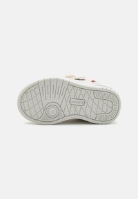 Suola delle sneaker Lacoste, in gomma bianca con un motivo di grip testurizzato, presenta un dettaglio circolare e il logo del marchio, progettata per offrire aderenza e durata.