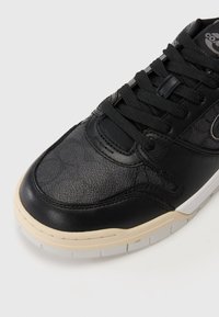 Fekete sneaker, textúrált bőr felsőrésszel, kontrasztos sima gumitalppal és fekete fűzőkkel. Finom logó található az oldalon.