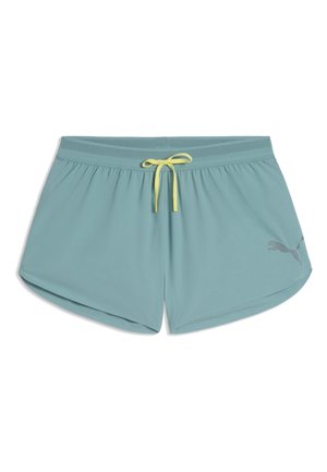Pantaloncini sportivi da donna azzurri chiaro con coulisse gialla e piccolo logo Puma sulla gamba destra, mostrati distesi su sfondo bianco.