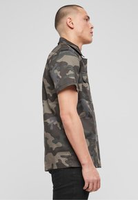 Camo kortekoope shirt in grijze en groene tinten, met een knoopsluiting bij de kraag, een borstzak en een rechte snit, gemaakt van lichtgewicht stof.