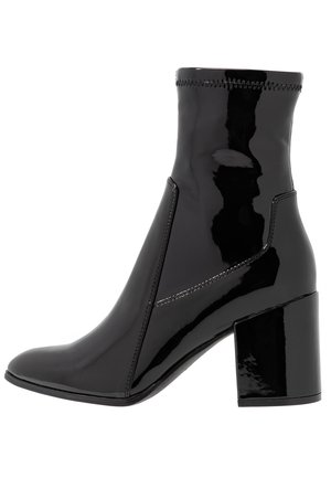 Botine negre din patent, cu o textură netedă, vârf ascuțit și un toc bloc structurat. Prezintă un design fără fermoar și cusături contrastante.