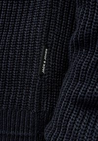Dunkelblaues gestricktes Sweatshirt mit einem strukturierten Muster. Beinhaltet ein Etikett mit "JACK & JONES" in Weiß auf schwarzem Hintergrund.