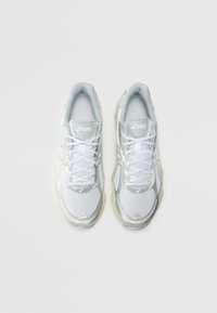 White athletic shoes with mesh fabric and metallic silver accents. Features round toe, lace-up design, and padded collar.