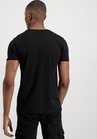 Schwarzes Kurzarm-T-Shirt aus weichem Baumwollmaterial mit slim Fit, runden Ausschnitt und glatter Oberfläche. Keine sichtbaren Logos oder Muster.