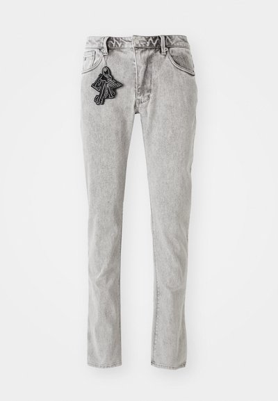 Light gray straight-leg denim jeans with a zipper fly, five pockets, and a decorative black keychain accent on the front.