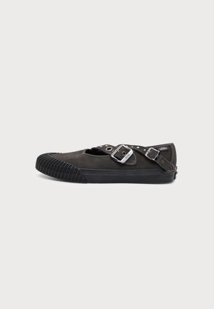 Čierna Vans slip-on obuv so gumovou špičkou, dvojitými kovovými prackami a plochou podrážkou na jednoduchom svetlom pozadí.
