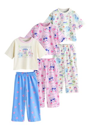 Tres conjuntos de camisetas de manga corta y pantalones para niños con dibujos animados coloridos de animales y corazones, colocados planos sobre un fondo blanco.
