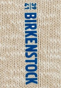 Etichetta Birkenstock su uno sfondo di tessuto intrecciato beige, con il testo blu in grassetto "BIRKENSTOCK" e indicatori di taglia "39/41" in uno stile contrastante.