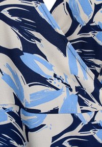 Modrý a krémový textil s květinovým vzorem a texturovaným povrchem. Design obsahuje abstraktní květiny na tmavě modrém pozadí.