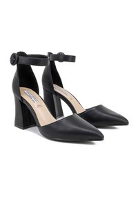 Scarpe nere in pelle con tacco alto, punta affusolata, cinturino alla caviglia e tacco a blocco. Texture liscia con soletta beige, design semplice.