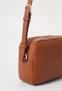Borsa a tracolla in pelle marrone con finitura testurizzata, forma rettangolare, dettaglio della cerniera dorata e tracolla regolabile.