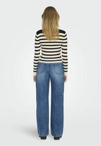 Randig svart och vit ribbad långärmad topp kombinerad med ljusblå vida jeans, med en femfickdesign.