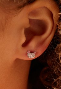 Kat-vormige studoorbel met een zilveren basis, voorzien van een sprankelende edelsteenvlakte en roze emaille accenten op de oren.