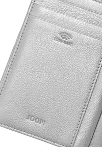 Stříbrný kožený držák na karty s více přihrádkami na karty, embosované logo a symbol bezdrátového signálu. Měkká textura s jemným šitím.