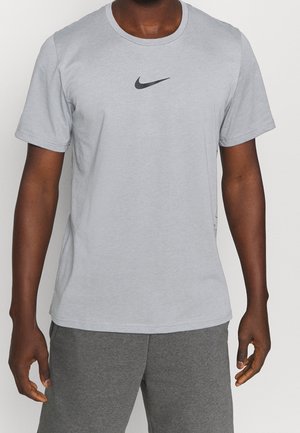 Lysgrå kortærmet T-shirt lavet af blødt stof, med et sort Nike-logo centreret på brystet og en klassisk rund halsudskæring.