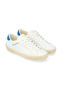 Sneakers bianchi in pelle con dettagli blu sul tallone, lacci piatti e una suola in gomma beige testurizzata. Presentano un decorativo dettaglio di cucitura nera.