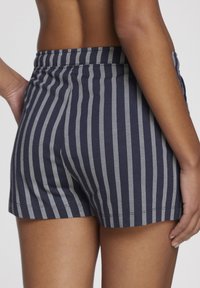 Navy blue shorts with white vertical stripes, featuring a soft texture and an elastic waistband, finishing just above the thigh.