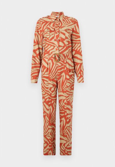 Combinaison à manches longues avec un motif abstrait orange et crème. Comprend deux poches poitrine, une taille ceinturée et un devant à boutons. Fabriquée en tissu léger.