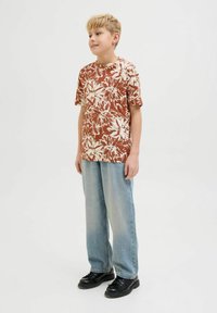 Camisa corta de manga corta marrón con patrones blancos, combinada con jeans sueltos de un azul claro y zapatos negros. Diseño sencillo, ajuste casual.