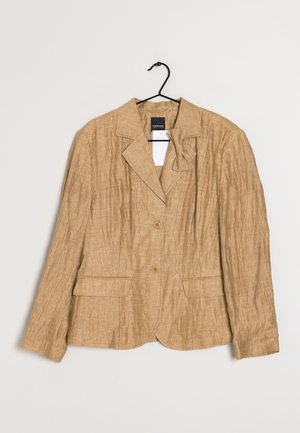 Blazer marron clair texturé avec deux boutons, col à revers cranté, détail de noeud côté gauche et poches à rabat devant, accroché sur un cintre noir.