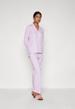 Ljuslila pyjamas सेट med vertikala vita ränder, med skjorta med krage och rakbenade byxor. Bärs med rosa pälssandaler.
