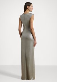Rochie lungă, mulată, dintr-un material metalic argintiu. Are mâneci tip cap, decolteu oval și fermoar ascuns la spate. Textură netedă.