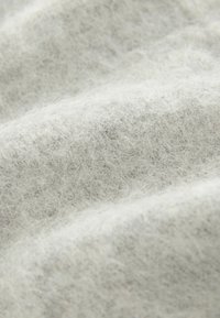 Soft grey fabric with a fuzzy texture, featuring subtle variations in shade and a dense, woven pattern. Ideal for warmth and comfort.