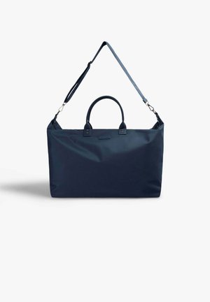Bolsa de viaje rectangular azul marino con dos asas cortas y una correa de hombro ajustable, sobre un fondo blanco.